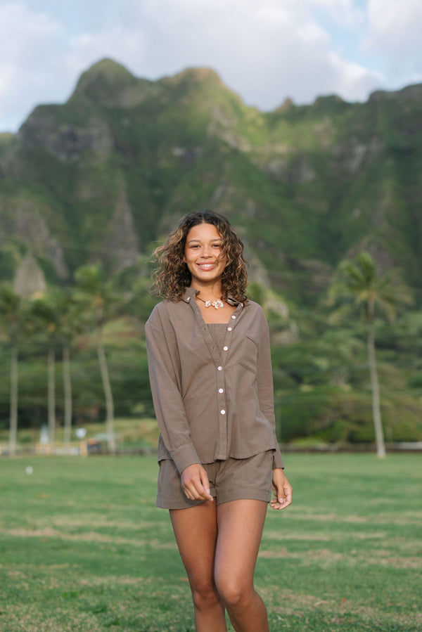 Woman wearing loose button up, smocked tube top and short in medium brown linen.