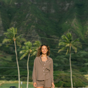 Woman wearing loose button up, smocked tube top and short in medium brown linen.
