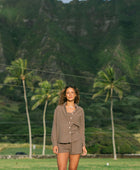 Woman wearing loose button up, smocked tube top and short in medium brown linen.