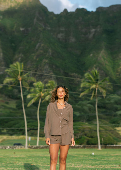 Woman wearing loose button up, smocked tube top and short in medium brown linen.