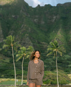 Woman wearing loose button up, smocked tube top and short in medium brown linen.