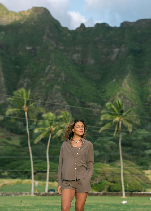 Woman wearing loose button up, smocked tube top and short in medium brown linen.