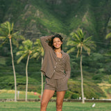 Woman wearing loose button up, smocked tube top and short in medium brown linen.
