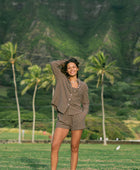 Woman wearing loose button up, smocked tube top and short in medium brown linen.