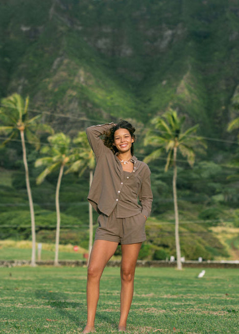 Woman wearing loose button up, smocked tube top and short in medium brown linen.