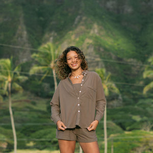 Woman wearing loose button up, smocked tube top and short in medium brown linen.