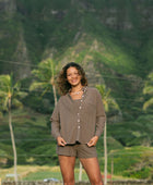 Woman wearing loose button up, smocked tube top and short in medium brown linen.