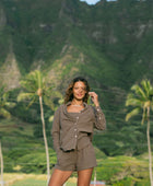 Woman wearing loose button up, smocked tube top and short in medium brown linen.