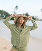 Woman wearing loose button up with smocked tube top and short in medium green linen.