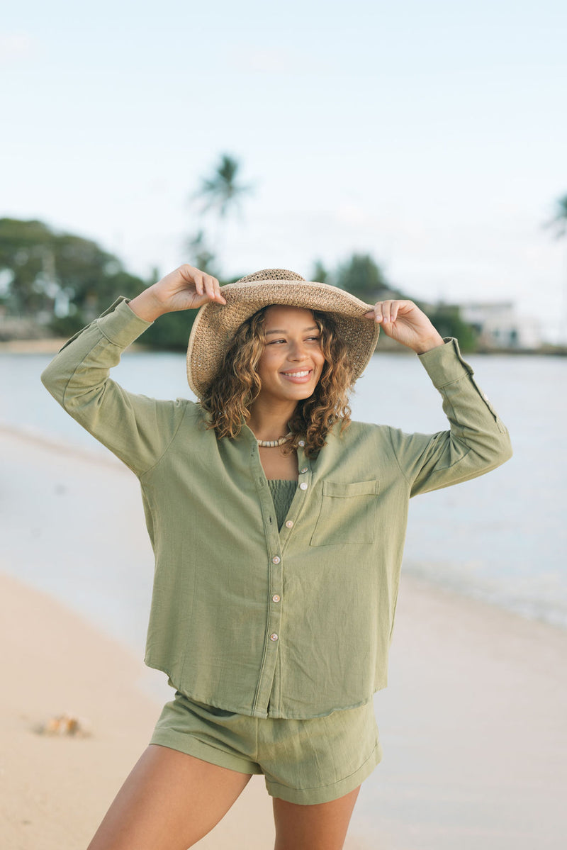 Woman wearing loose button up with smocked tube top and short in medium green linen.