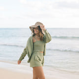 Woman wearing loose button up and smocked tube top with spaghetti straps and short in medium green linen.