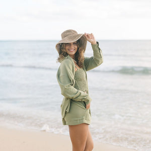 Woman wearing loose button up and smocked tube top with spaghetti straps and short in medium green linen.