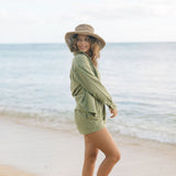 Woman wearing loose button up and smocked tube top with spaghetti straps and short in medium green linen.