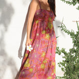 womean wearing terracotta colored tie back dress with large purple and yellow flower print