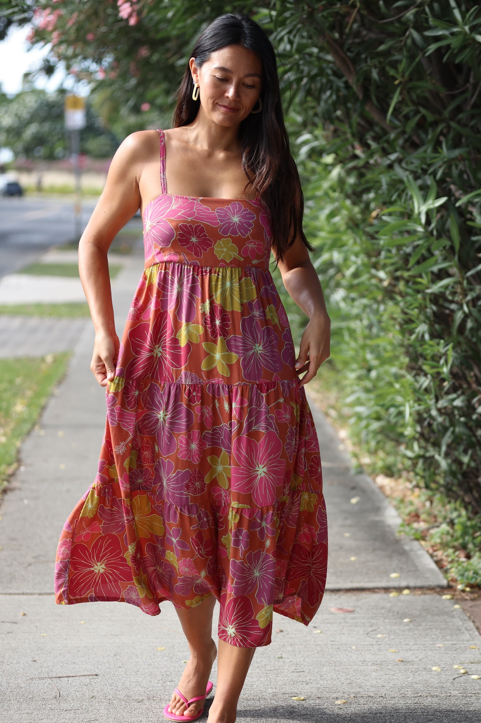 woman wearing terracotta colored tie back dress with large purple and yellow flower print