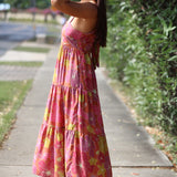 womean wearing terracotta colored tie back dress with large purple and yellow flower print