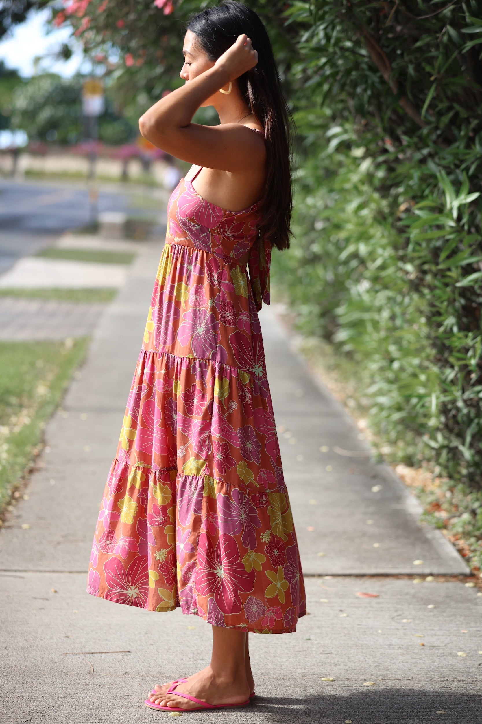 womean wearing terracotta colored tie back dress with large purple and yellow flower print
