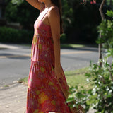 woman wearing terracotta colored tie back dress with large purple and yellow flower print