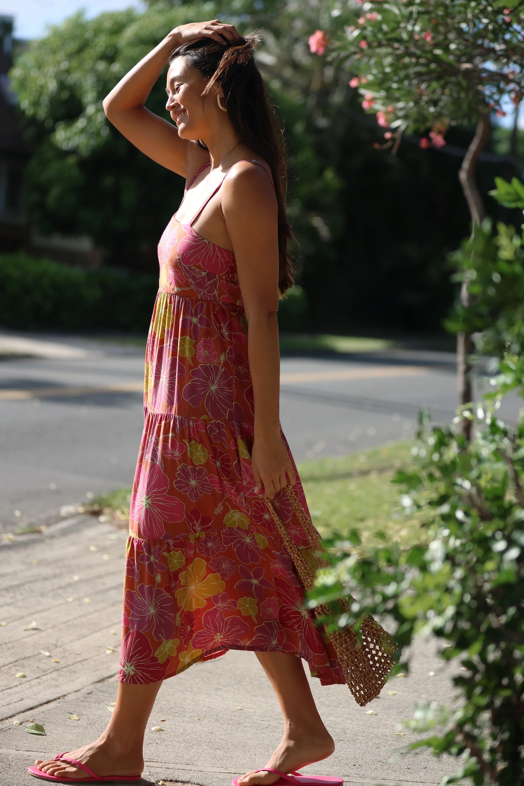 woman wearing terracotta colored tie back dress with large purple and yellow flower print