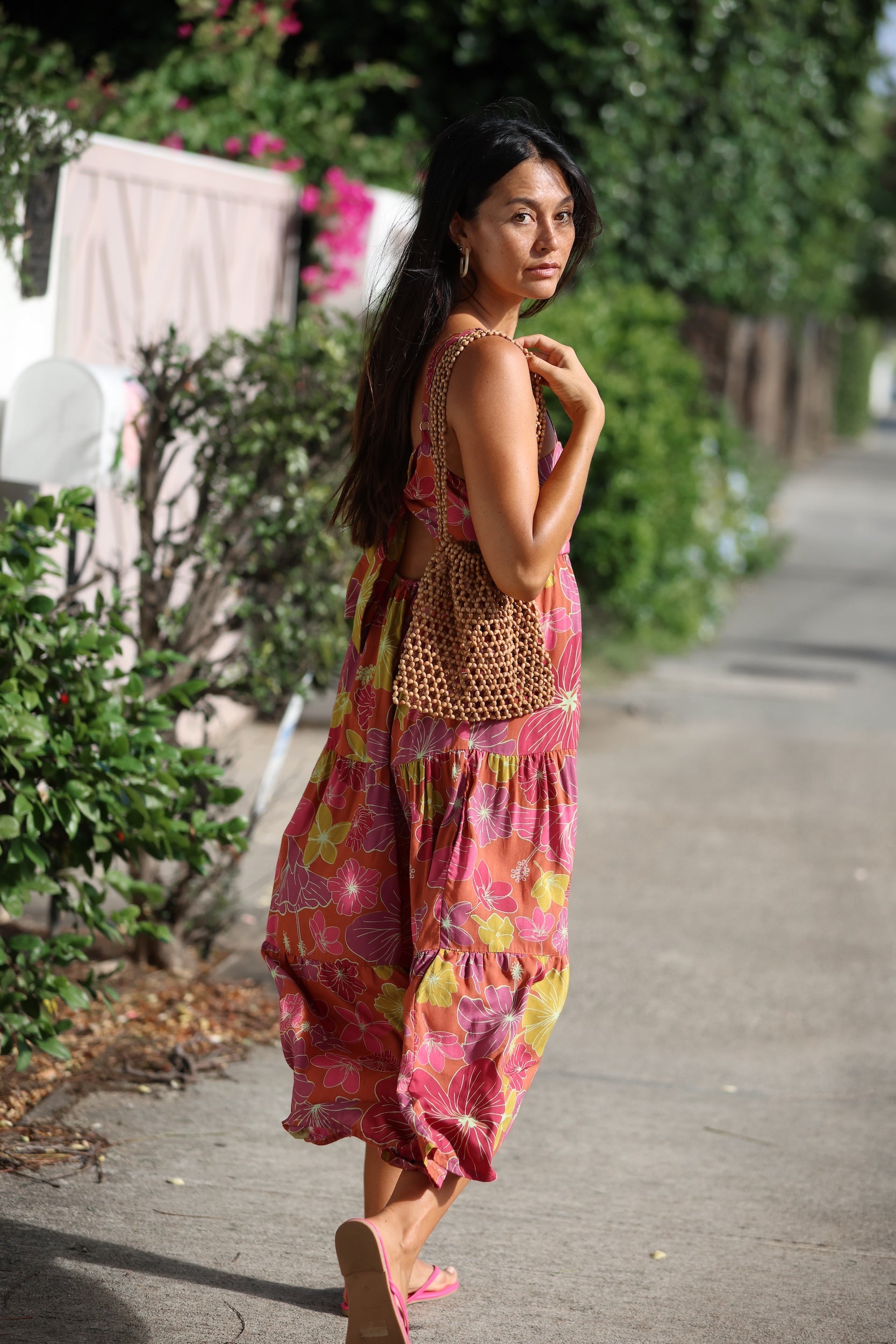 woman wearing terracotta colored tie back dress with large purple and yellow flower print