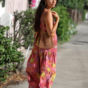 woman wearing terracotta colored tie back dress with large purple and yellow flower print