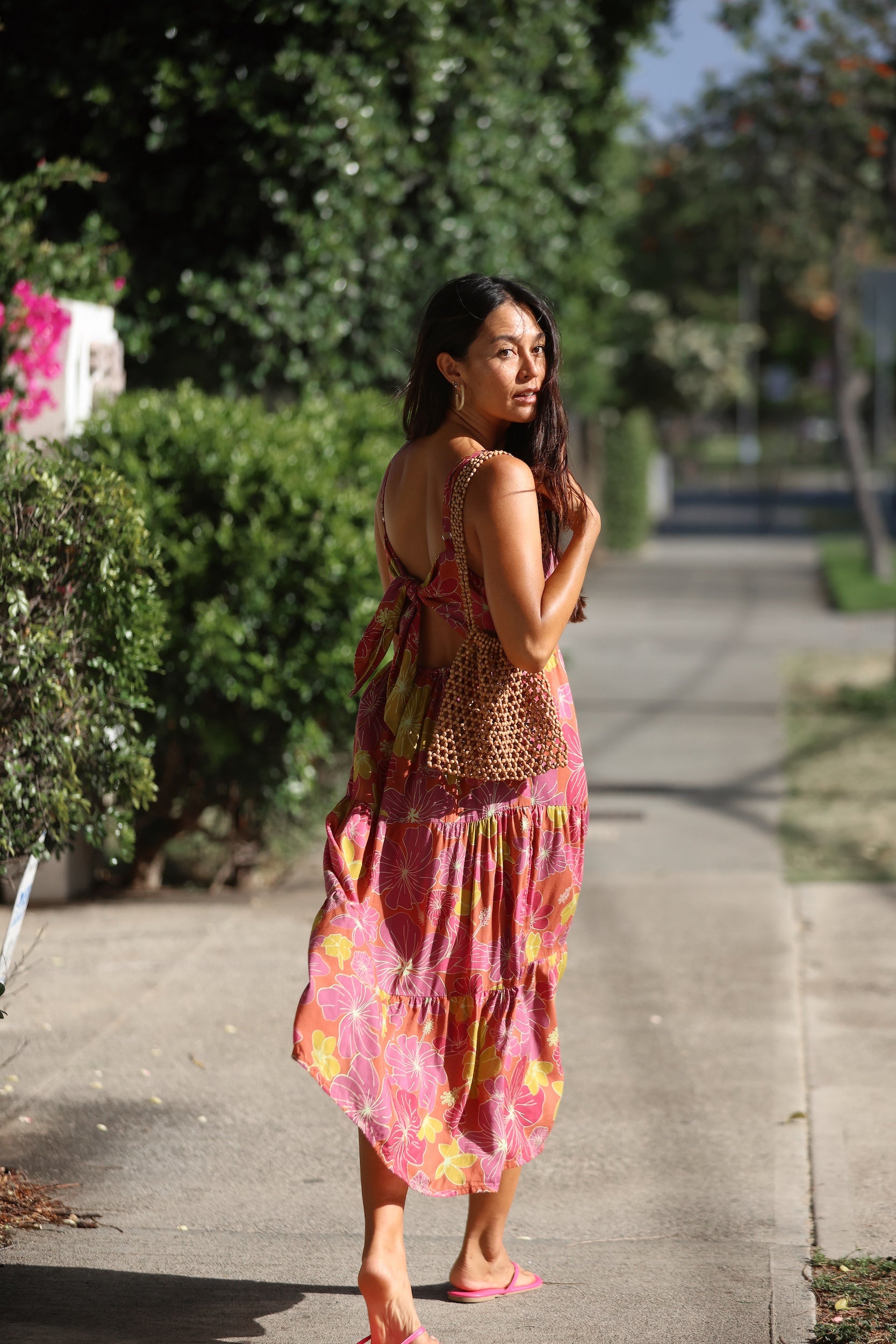 woman wearing terracotta colored tie back dress with large purple and yellow flower print