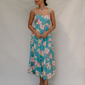 woman with brown hair wearing maxi tie back dress in teal with orchid pattern