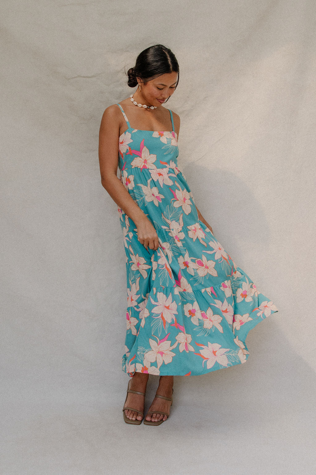 woman with brown hair wearing maxi tie back dress in teal with orchid pattern