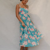 woman with brown hair wearing maxi tie back dress in teal with orchid pattern