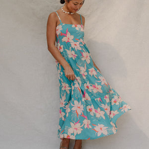woman with brown hair wearing maxi tie back dress in teal with orchid pattern