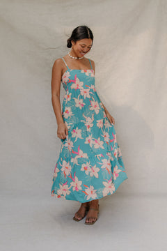 woman with brown hair wearing maxi tie back dress in teal with orchid pattern