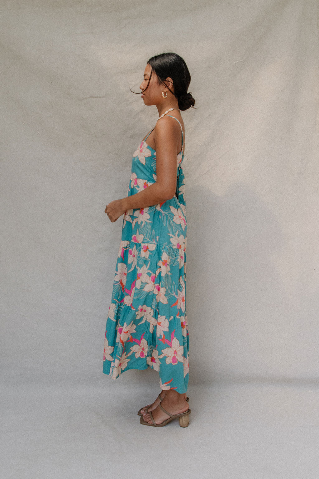 woman with brown hair wearing maxi tie back dress in teal with orchid pattern