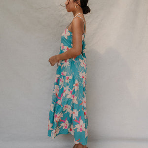 woman with brown hair wearing maxi tie back dress in teal with orchid pattern