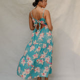 woman with brown hair wearing maxi tie back dress in teal with orchid pattern