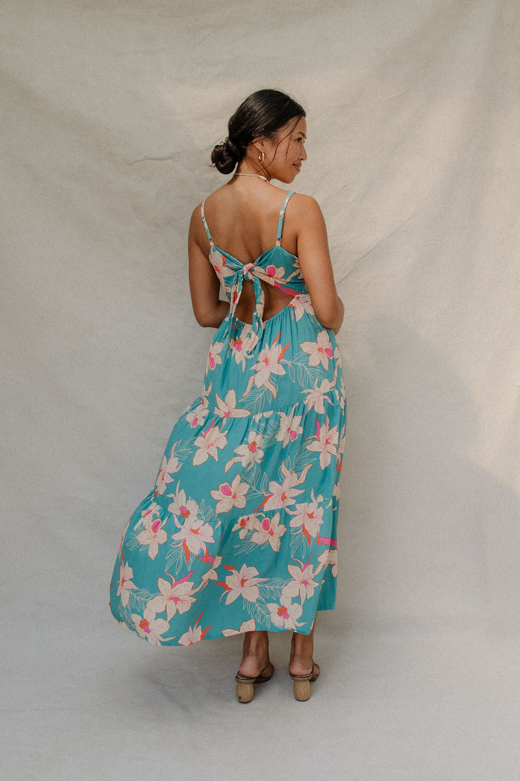 woman with brown hair wearing maxi tie back dress in teal with orchid pattern