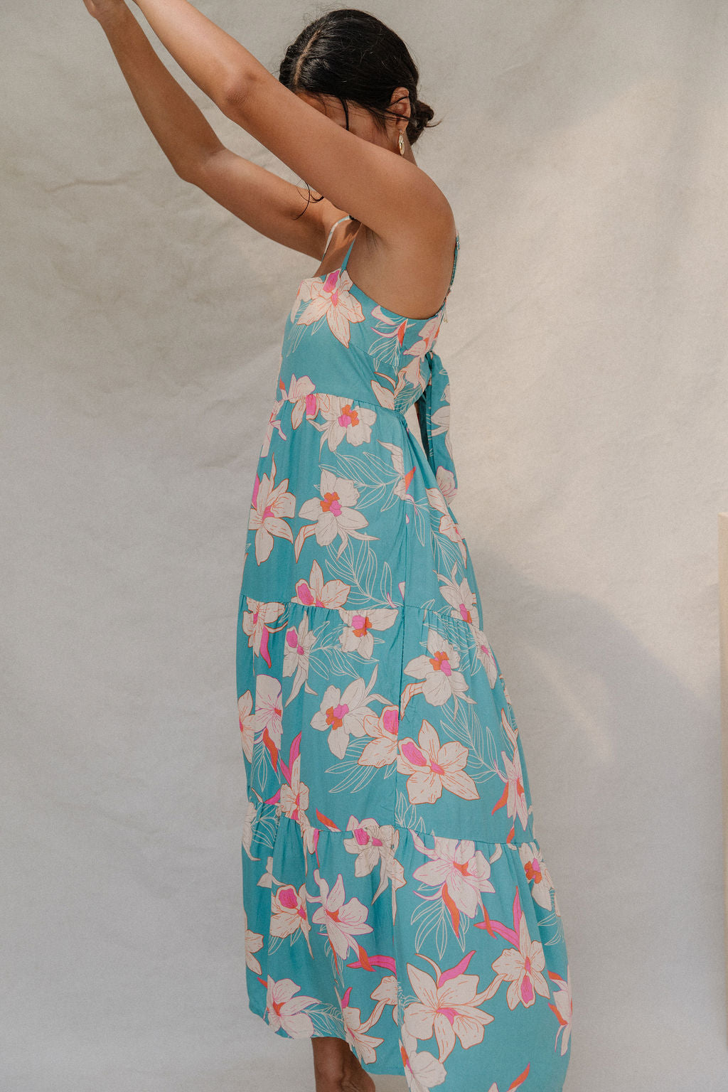 woman with brown hair wearing maxi tie back dress in teal with orchid pattern