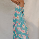 woman with brown hair wearing maxi tie back dress in teal with orchid pattern