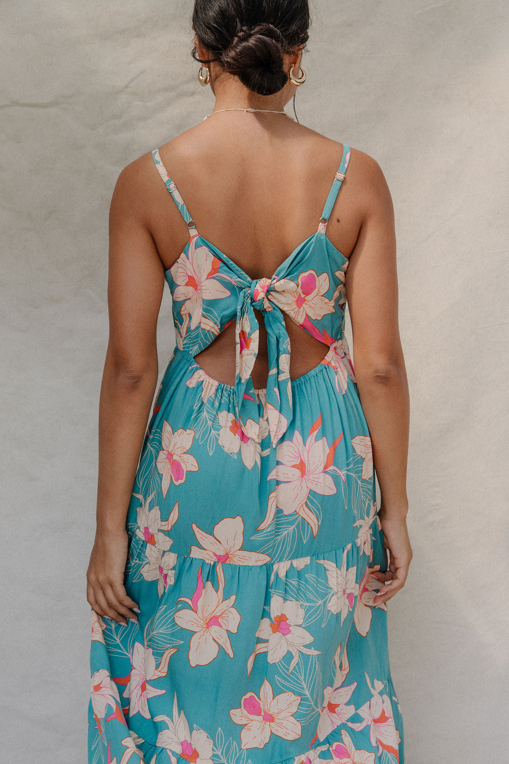woman with brown hair wearing maxi tie back dress in teal with orchid pattern