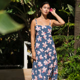 woman with black hair wearing a maxi tiered dress in a navy color with pink hibiscus blossoms 