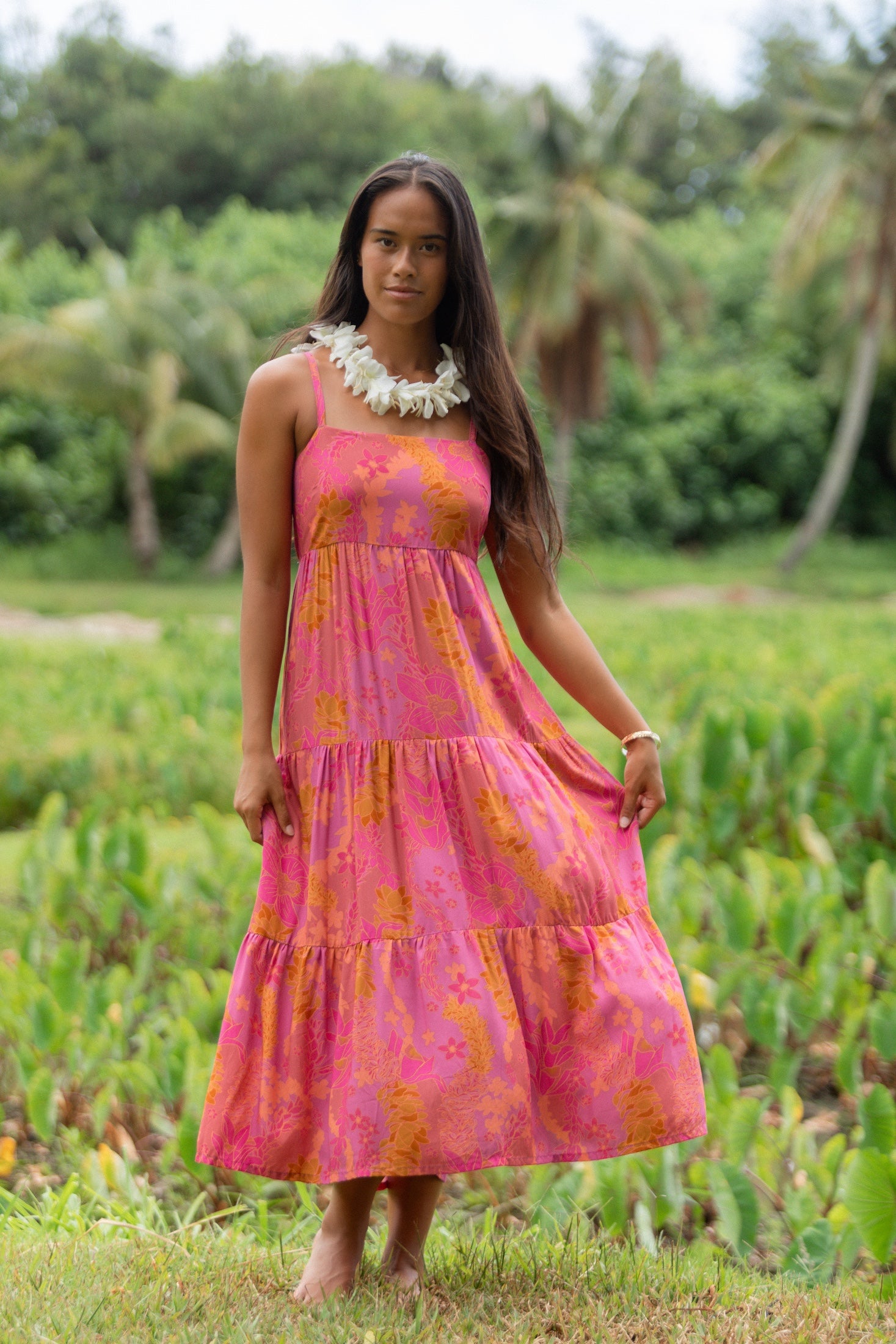 woman wearing a pink tie back maxi dress with lei print