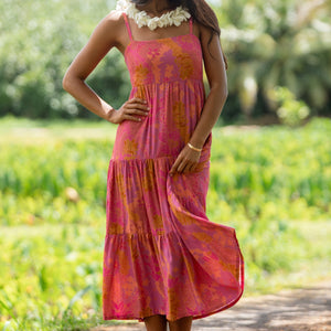 woman wearing a pink tie back maxi dress with lei print