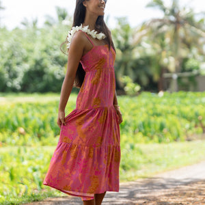 woman wearing a pink tie back maxi dress with lei print
