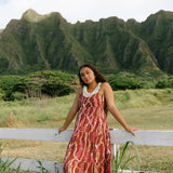 woman with brown hair wearing red-brown maxi dress with lei print
