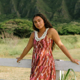 woman with brown hair wearing red-brown maxi dress with lei print