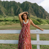 woman with brown hair wearing red-brown maxi dress with lei print