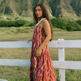 woman with brown hair wearing red-brown maxi dress with lei print