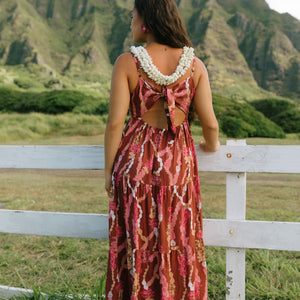 woman with brown hair wearing red-brown maxi dress with lei print