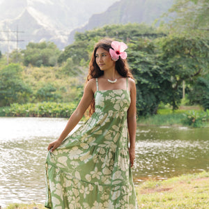 woman with brown hair wearing green tie back dress with native hawaiian plants