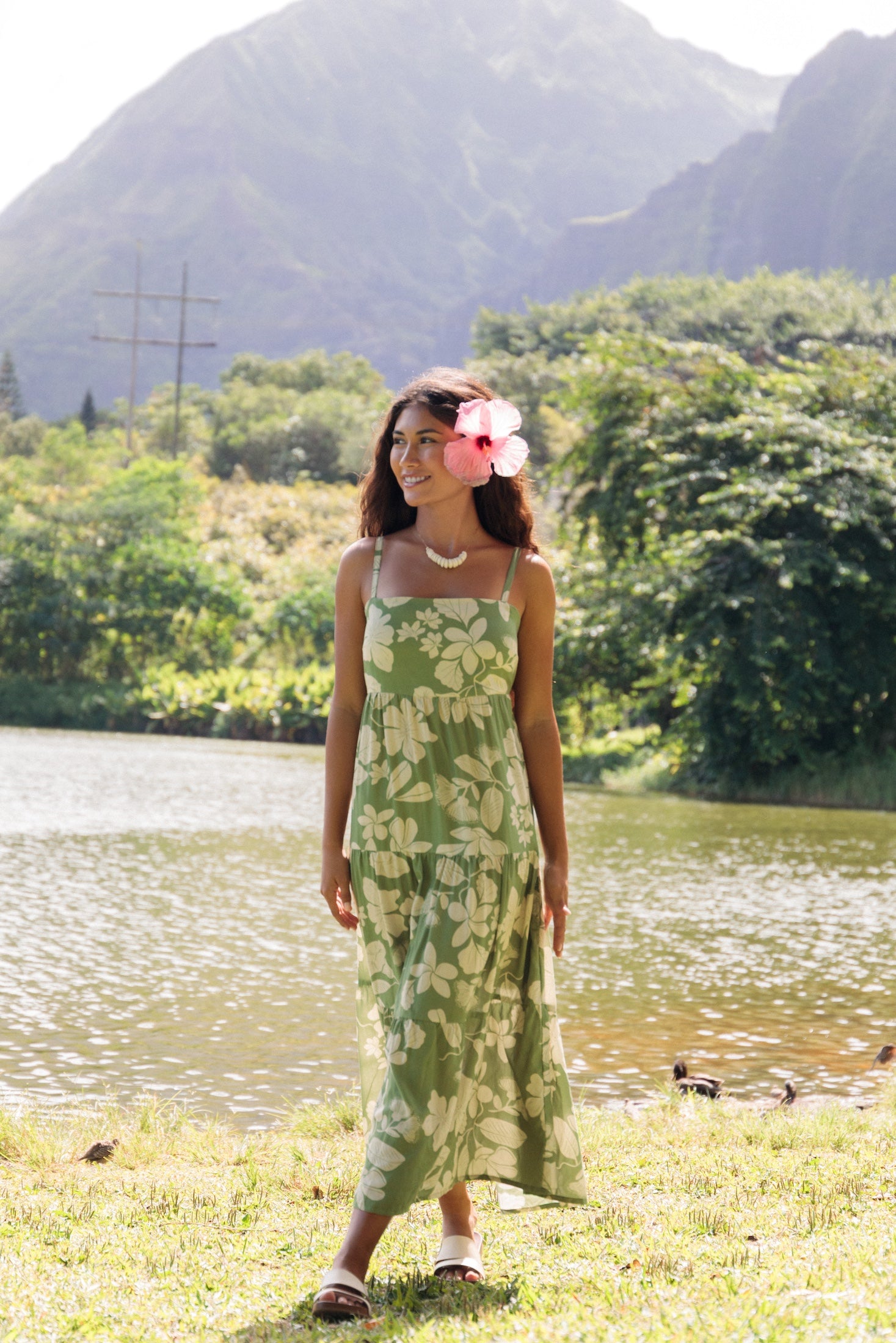woman with brown hair wearing green tie back dress with native hawaiian plants