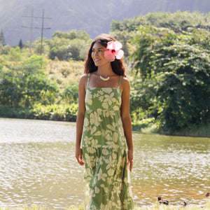 woman with brown hair wearing green tie back dress with native hawaiian plants